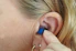 Close-up of a person gently inserting Kyrot earplugs before bedtime.