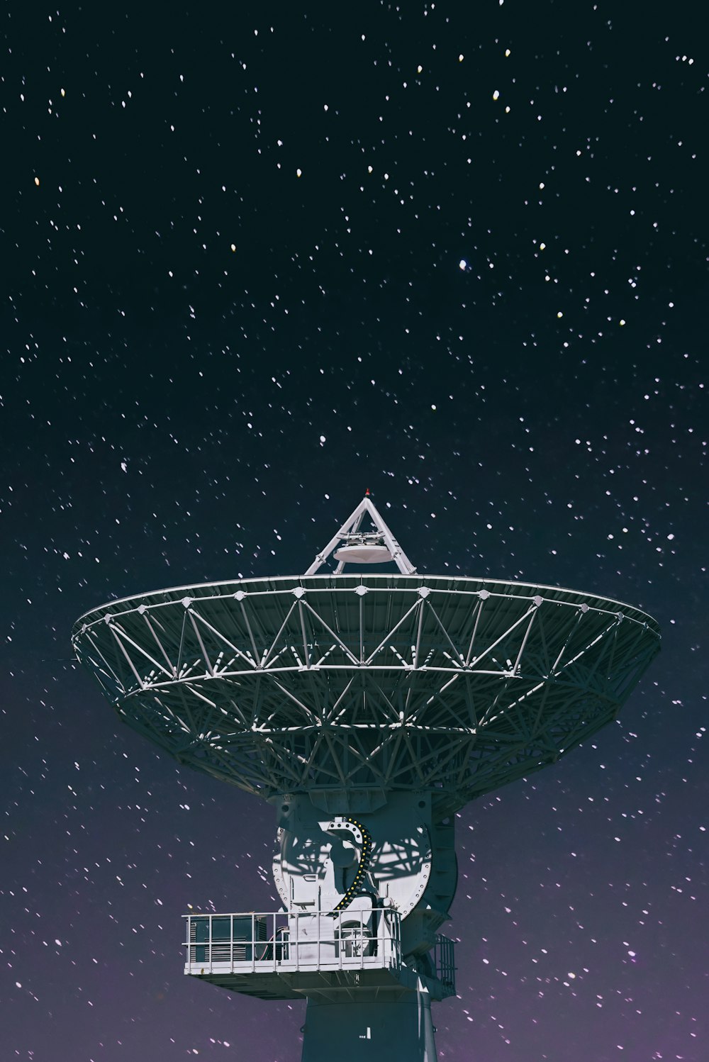 星降る夜の下の白い衛星放送受信アンテナ