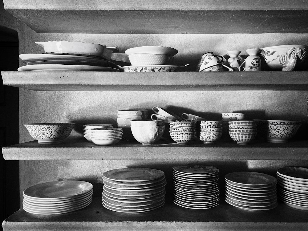 Foto en escala de grises de cuencos y platos de cerámica en una rejilla