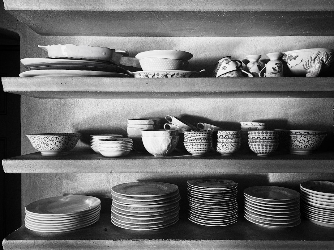 grayscale photo of ceramic bowls and plates on rack