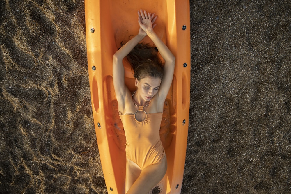 woman in yellow swimsuit lying on orange inflatable bed