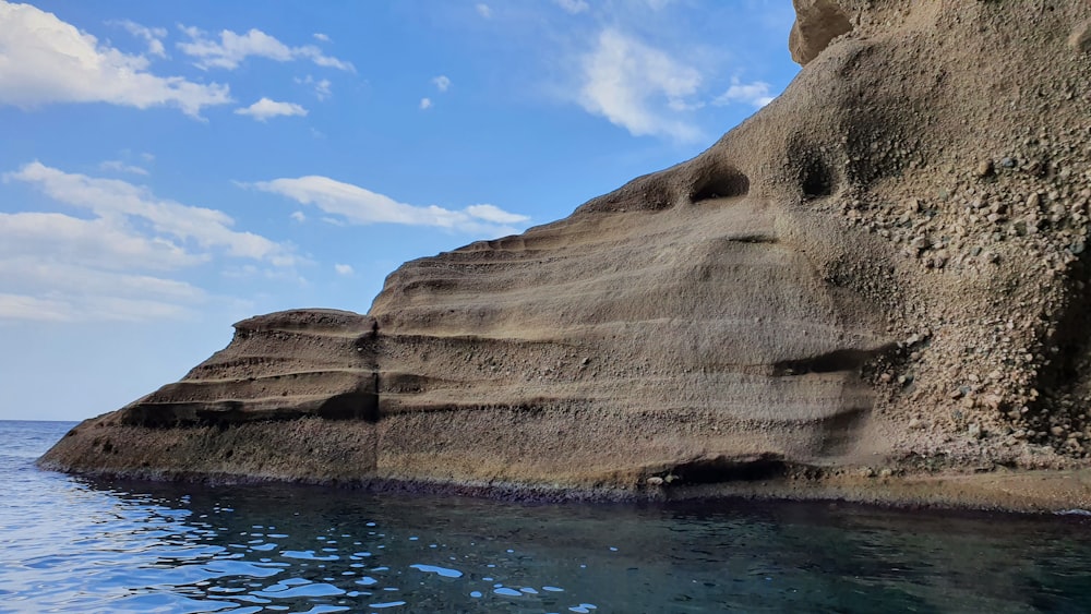 brown rock formation beside blue body of water during daytime