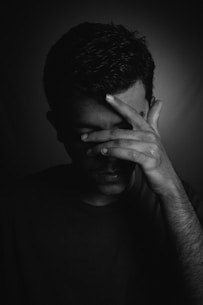 man in black crew neck shirt covering his face