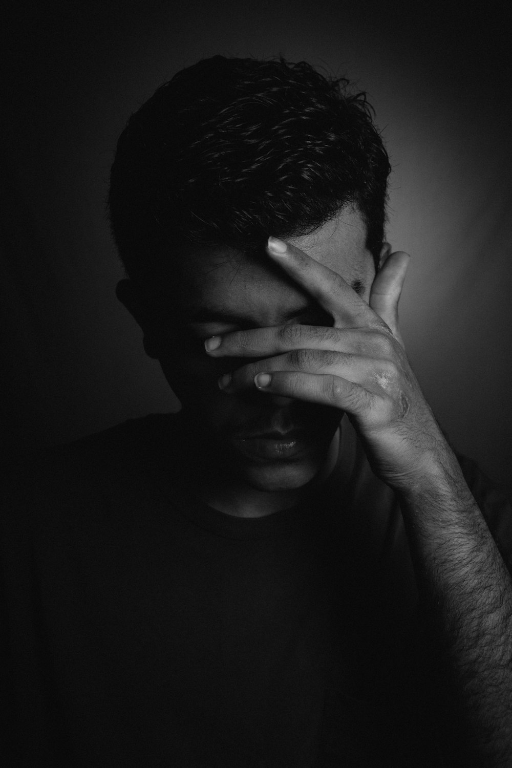 man in black crew neck shirt covering his face