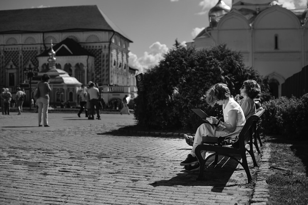 grayscale photo of man and woman sitting on bench