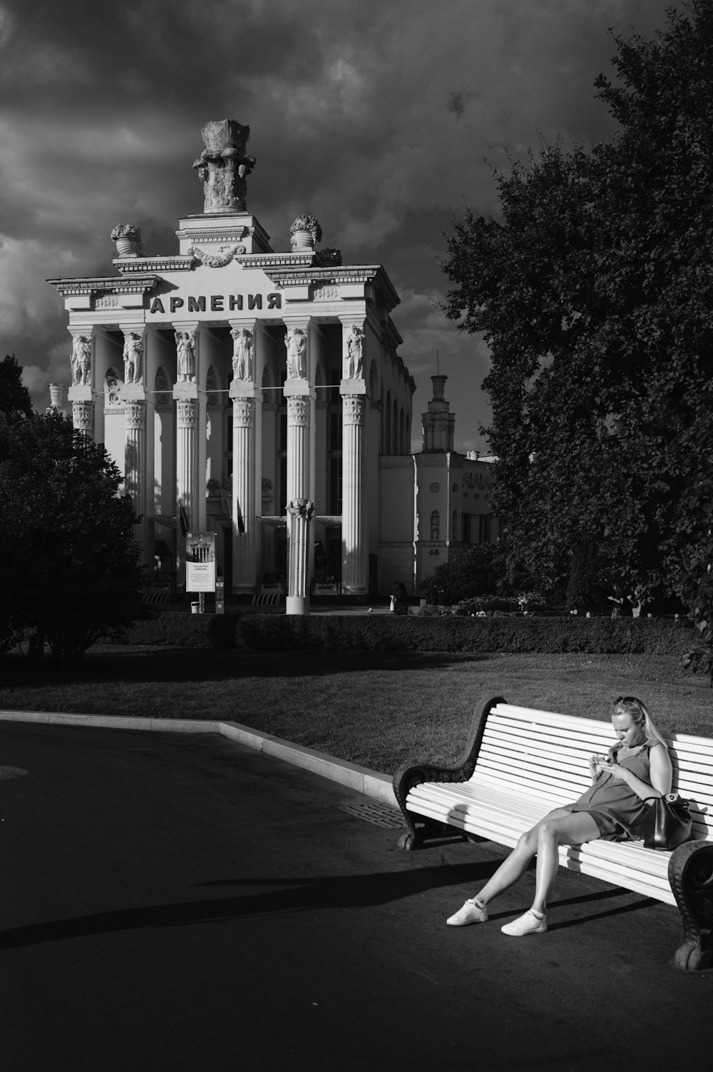 grayscale photo of man sitting on bench