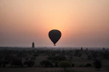 A vibrant hot air balloon floating gently over the ancient ruins of Luxor at dawn.