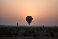 A vibrant hot air balloon floating serenely over the ancient Valley of the Kings at dawn.