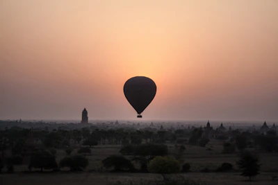A vibrant hot air balloon floating gently over Luxor’s ancient landscape at dawn.