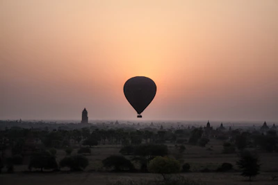 A vibrant hot air balloon floating gently over the ancient ruins of Luxor at dawn.