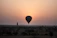 A serene hot air balloon drifting gently above ancient Luxor temples at dawn.