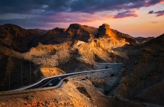 A breathtaking aerial shot of a winding mountain road at sunset.