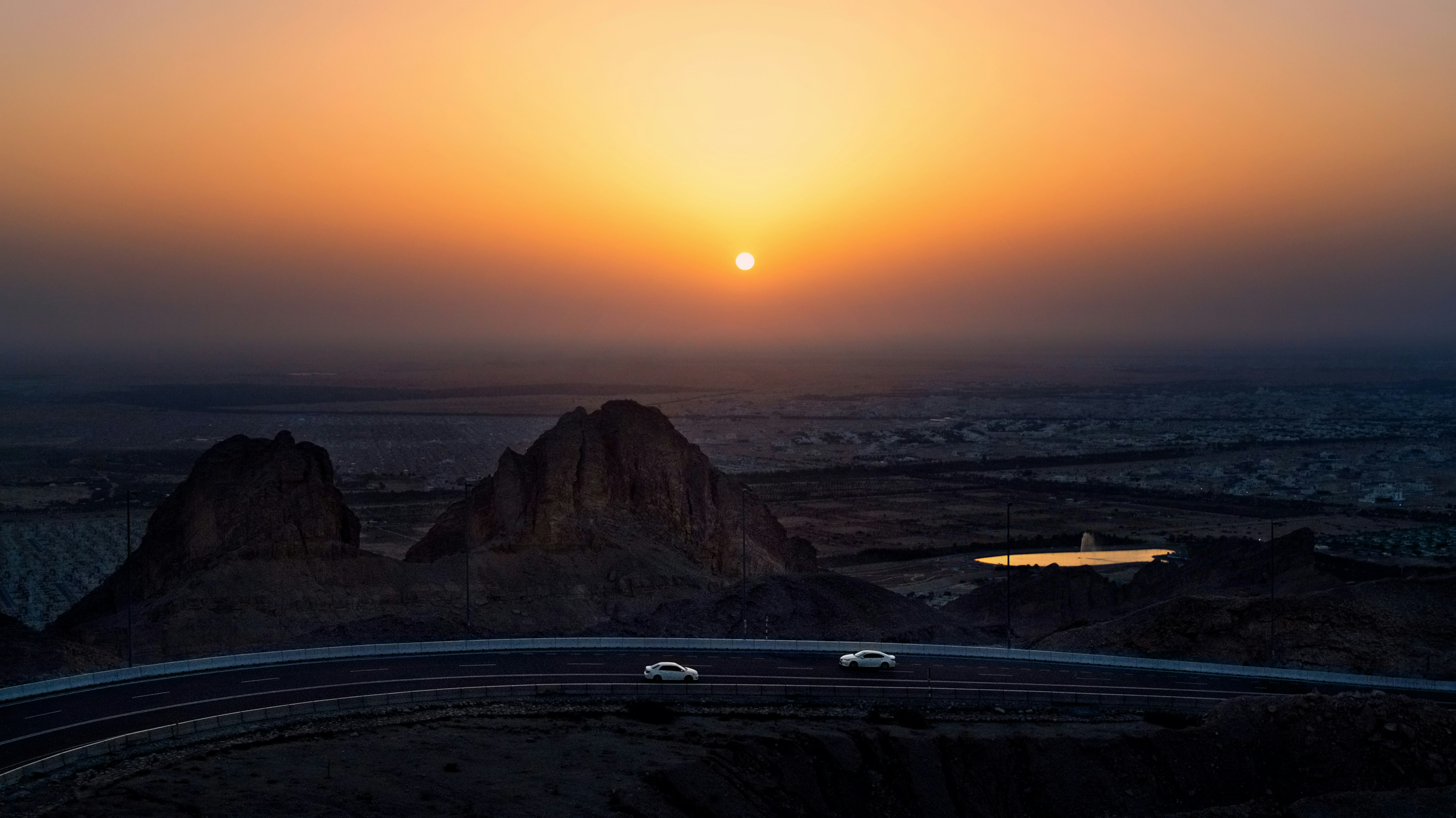 Coches en la carretera cerca de las montañas durante la puesta del sol