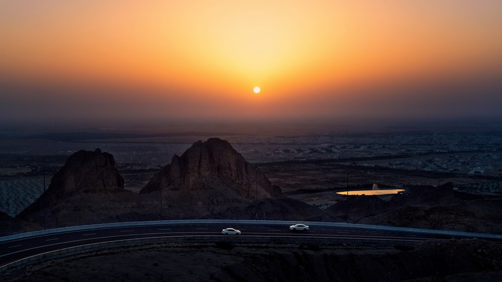 cars on road near mountains during sunset