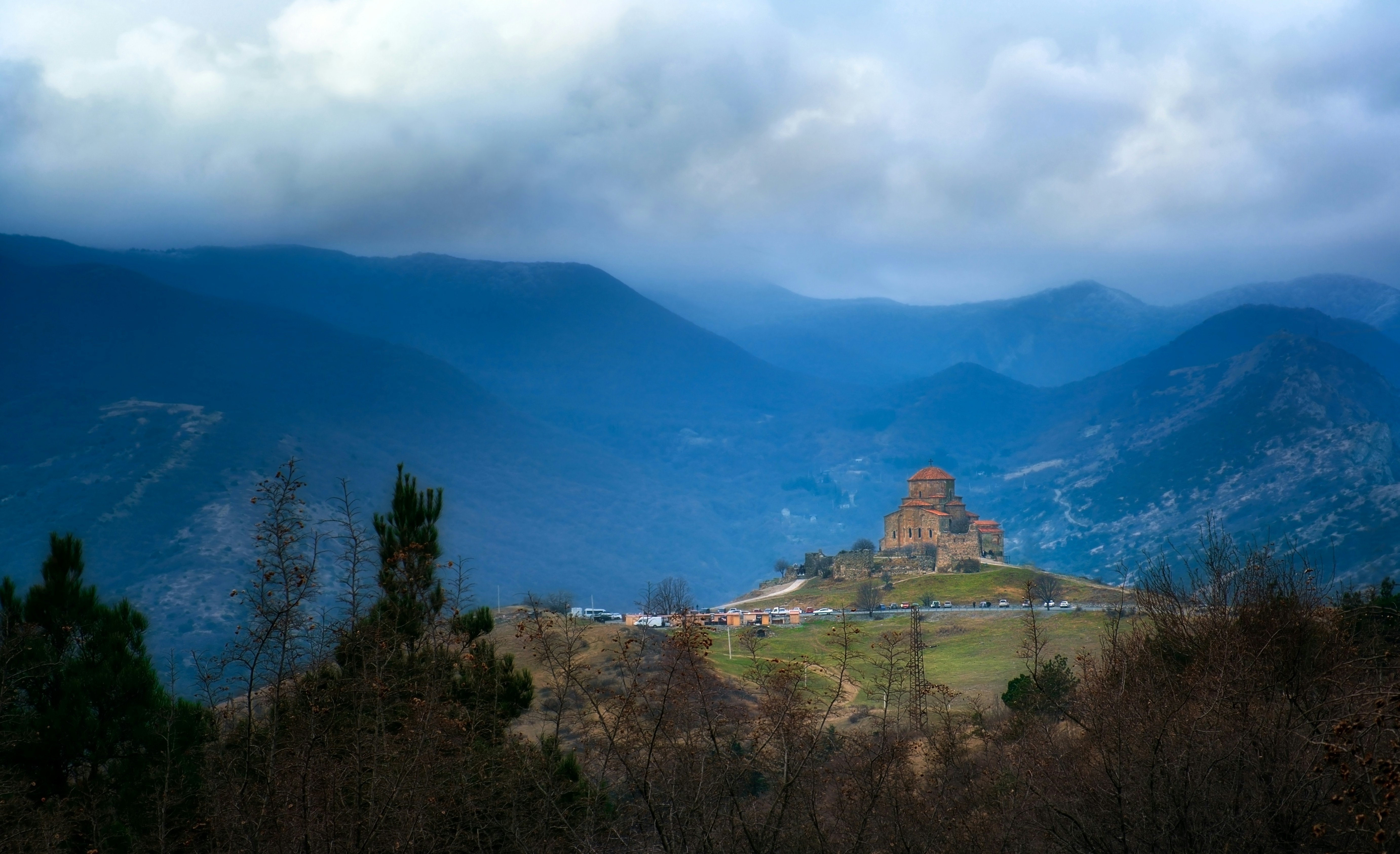 árboles verdes y montaña bajo nubes blancas y cielo azul durante el día