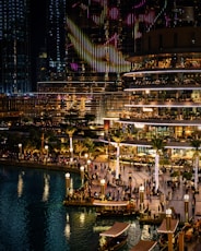 people walking on sidewalk near body of water during night time