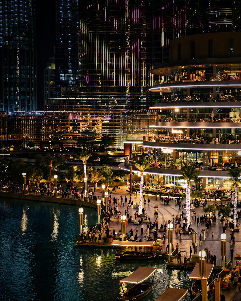 people walking on sidewalk near body of water during night time