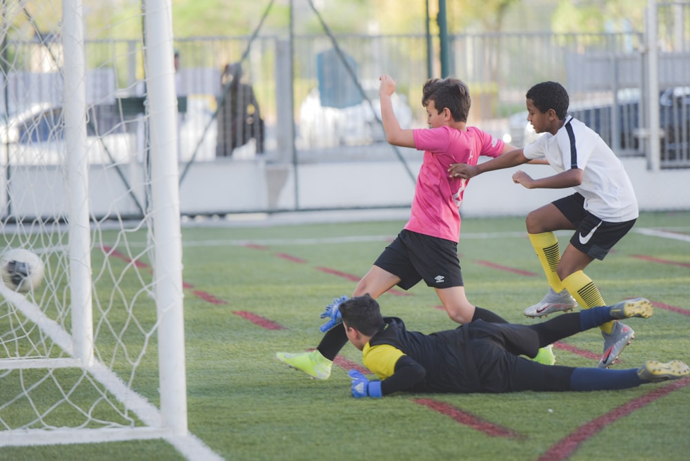 2 boys playing soccer on field during daytime