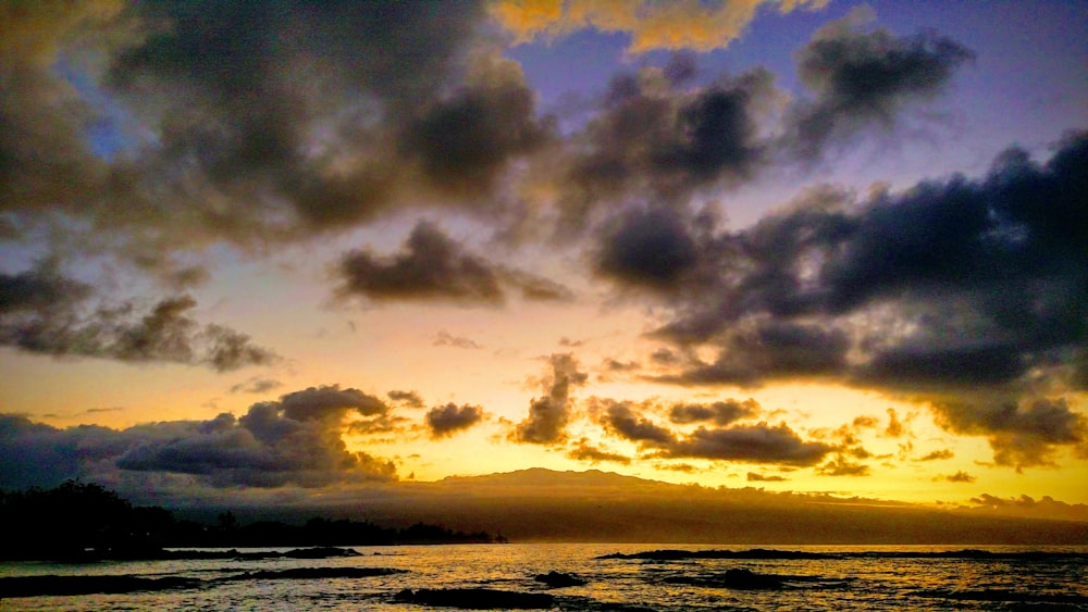 body of water under cloudy sky during sunset