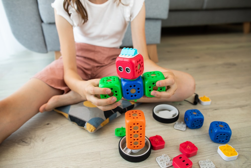 Mädchen im weißen Hemd spielt mit blauem und rotem Autospielzeug