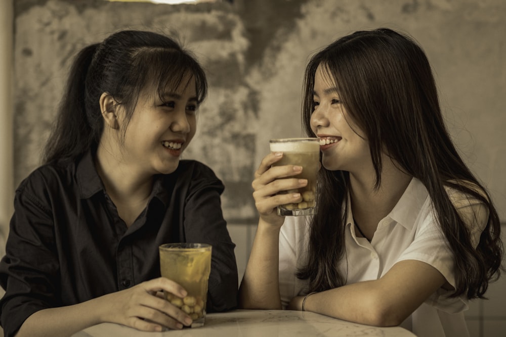 2 women holding drinking glasses