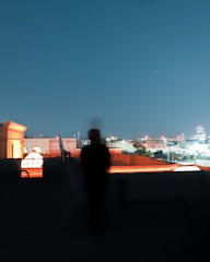 A shadowed figure observing a cityscape at night, symbolizing discreet surveillance