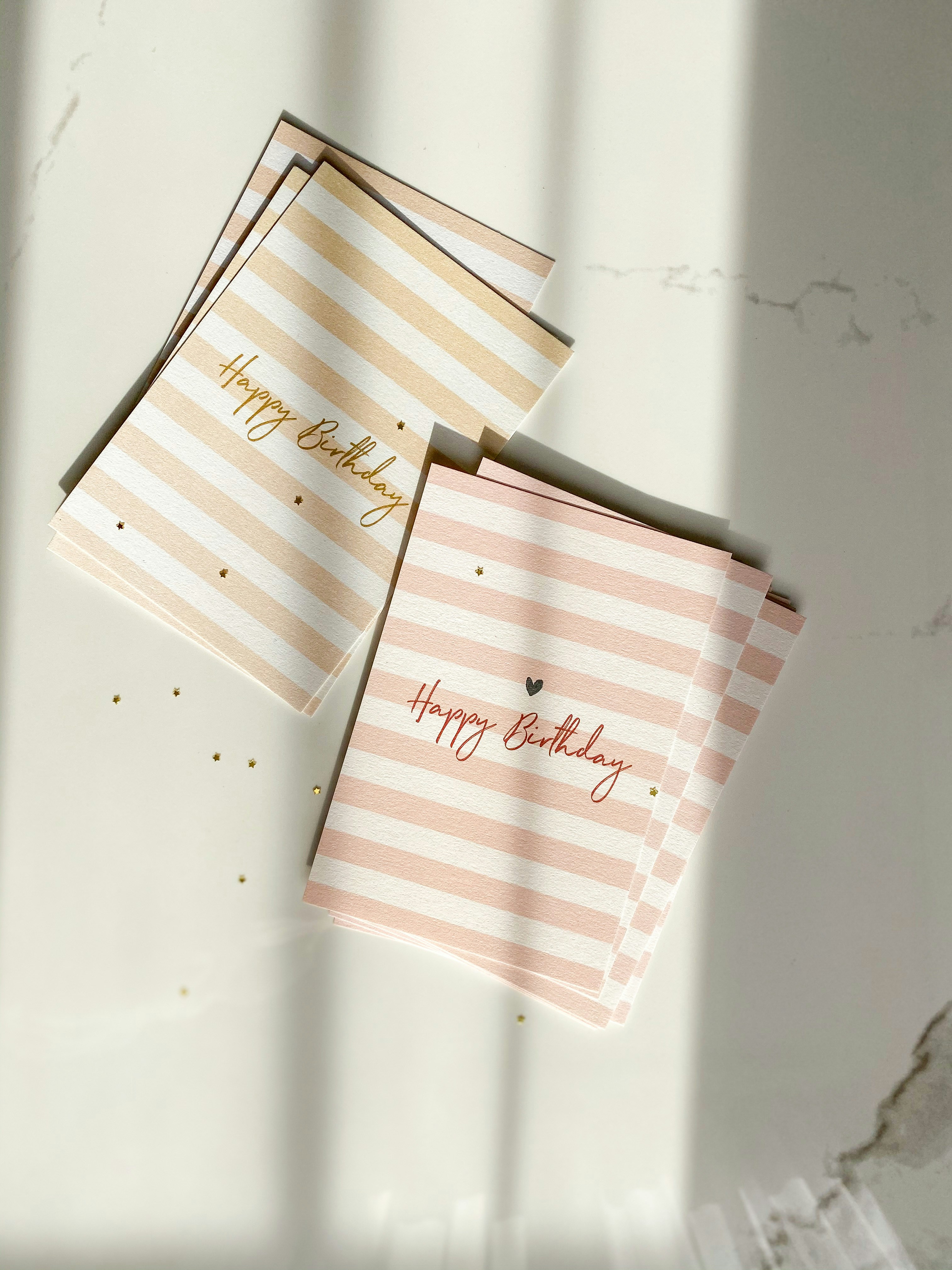 Colorful birthday cards with balloon designs and glitter accents spread on white surface