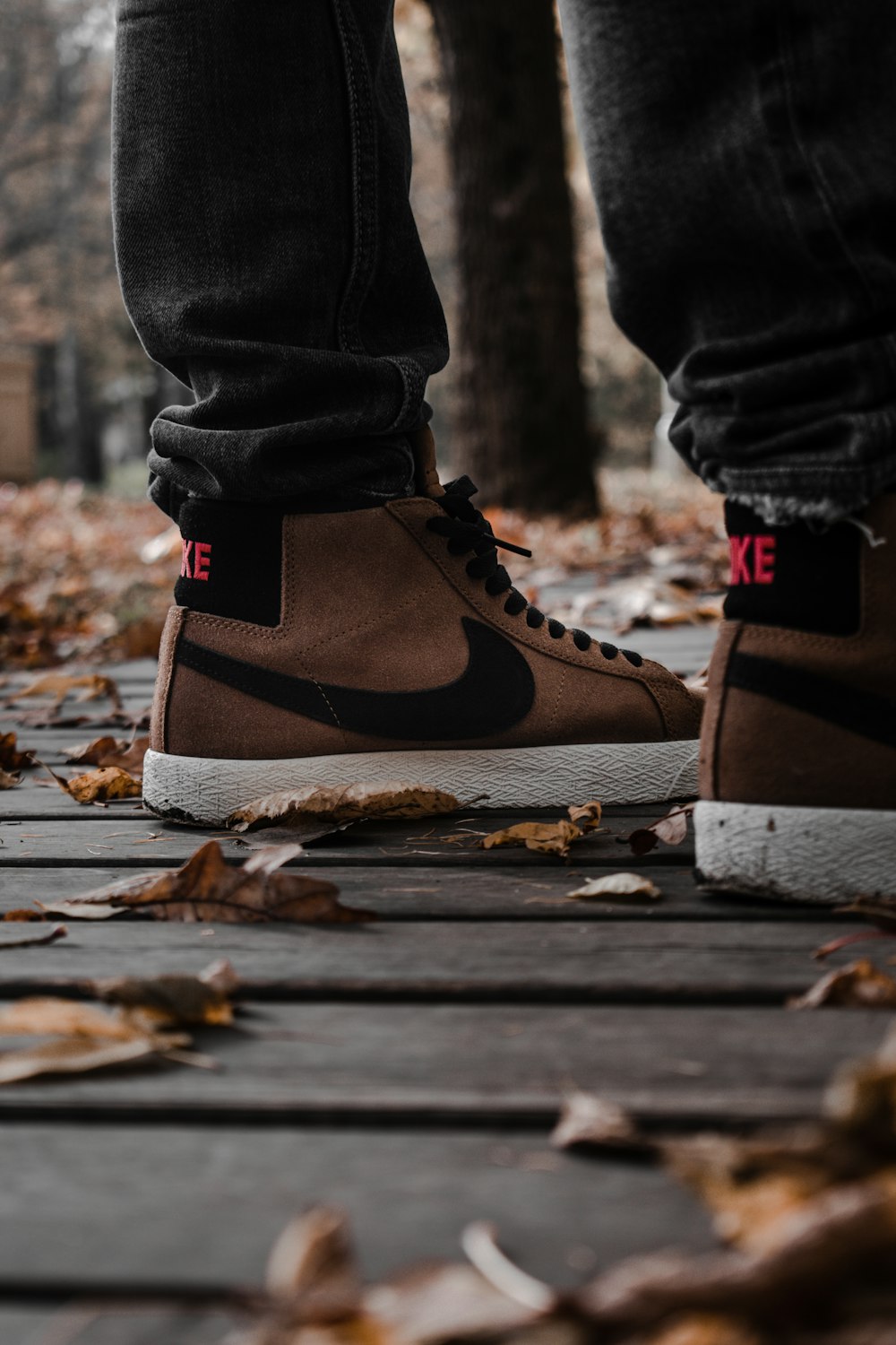 person in blue denim jeans and brown and white nike sneakers