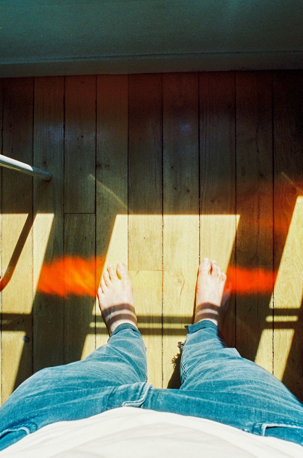 person in blue denim jeans standing on brown wooden floor