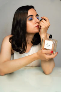 woman in white tank top holding perfume bottle