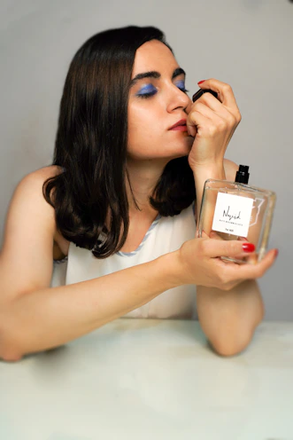 woman in white tank top holding perfume bottle