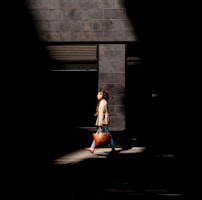A stylish woman carrying a luxe leather bag walking down a sunlit city street