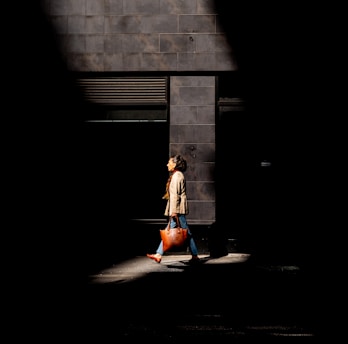 A stylish woman carrying a luxe leather bag walking down a sunlit city street