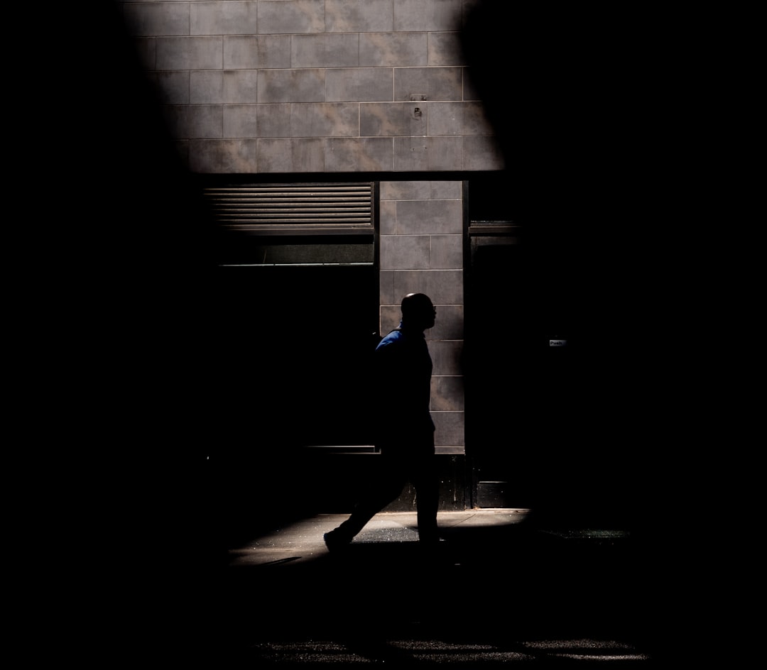 man in blue shirt standing near brick wall