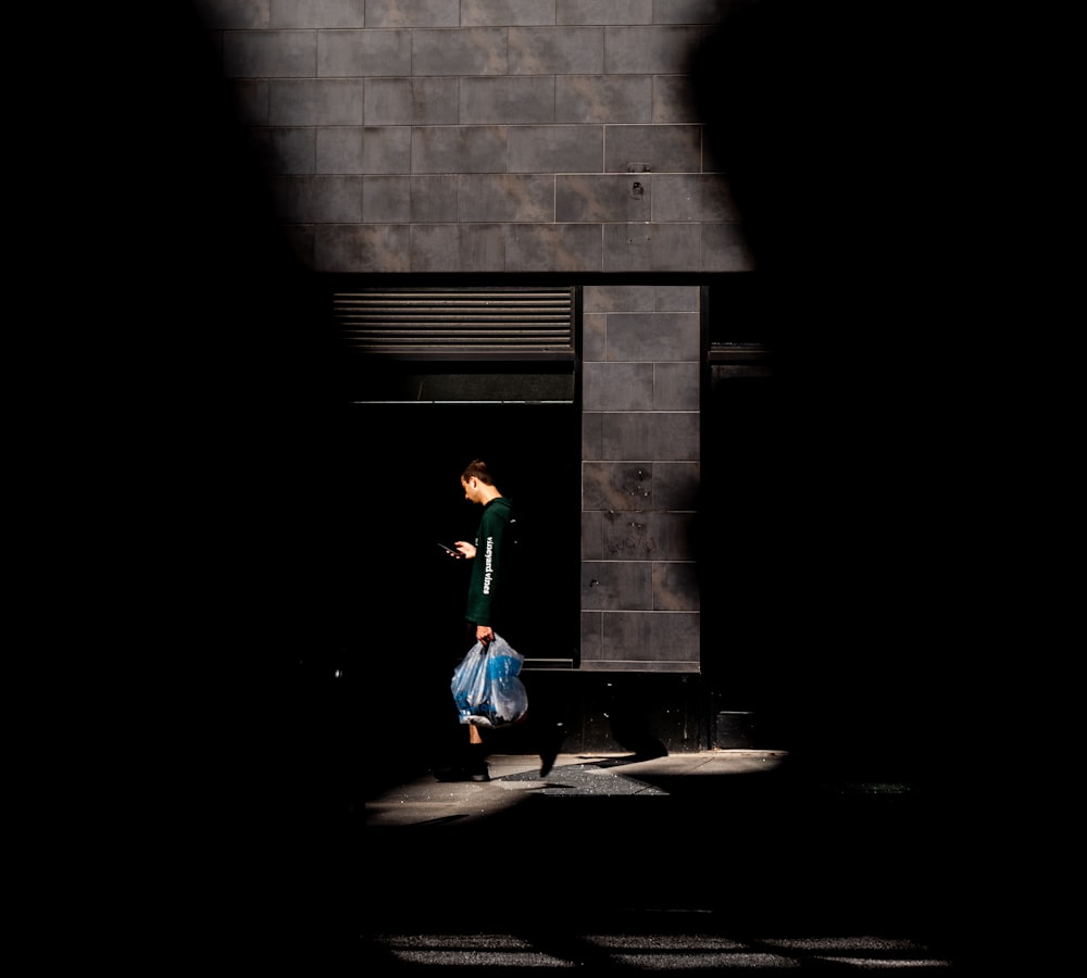 Chica con camisa verde de manga larga y pantalones azules caminando por la acera