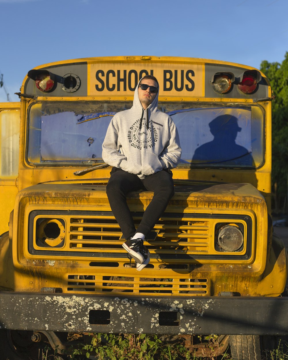 man in white dress shirt and black pants standing beside yellow school bus