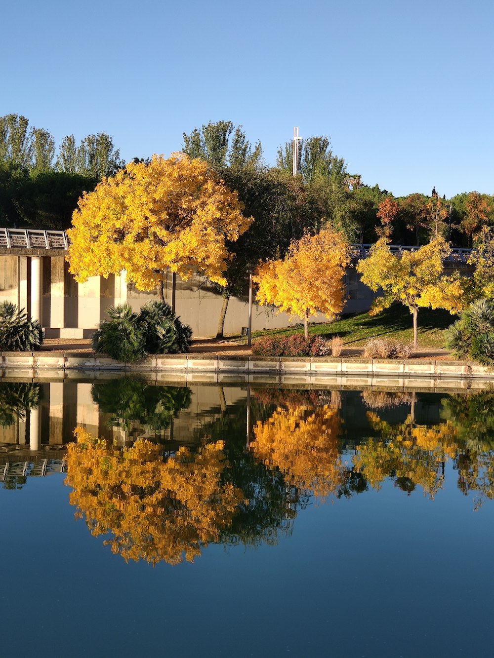 white concrete building near green trees and lake during daytime