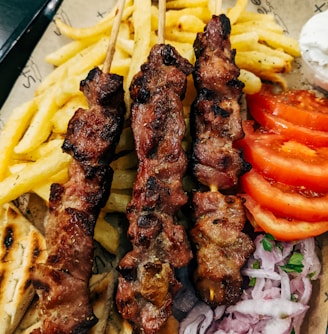 grilled meat with sliced tomato and green vegetable on white ceramic plate