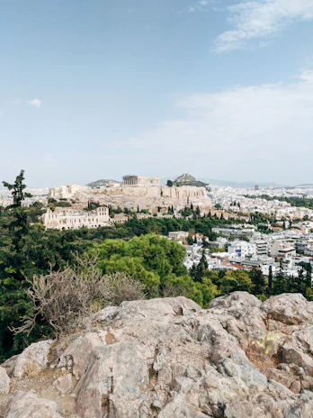 A dramatic view of the Acropolis hill with the Parthenon standing proudly under a cloudy sky.