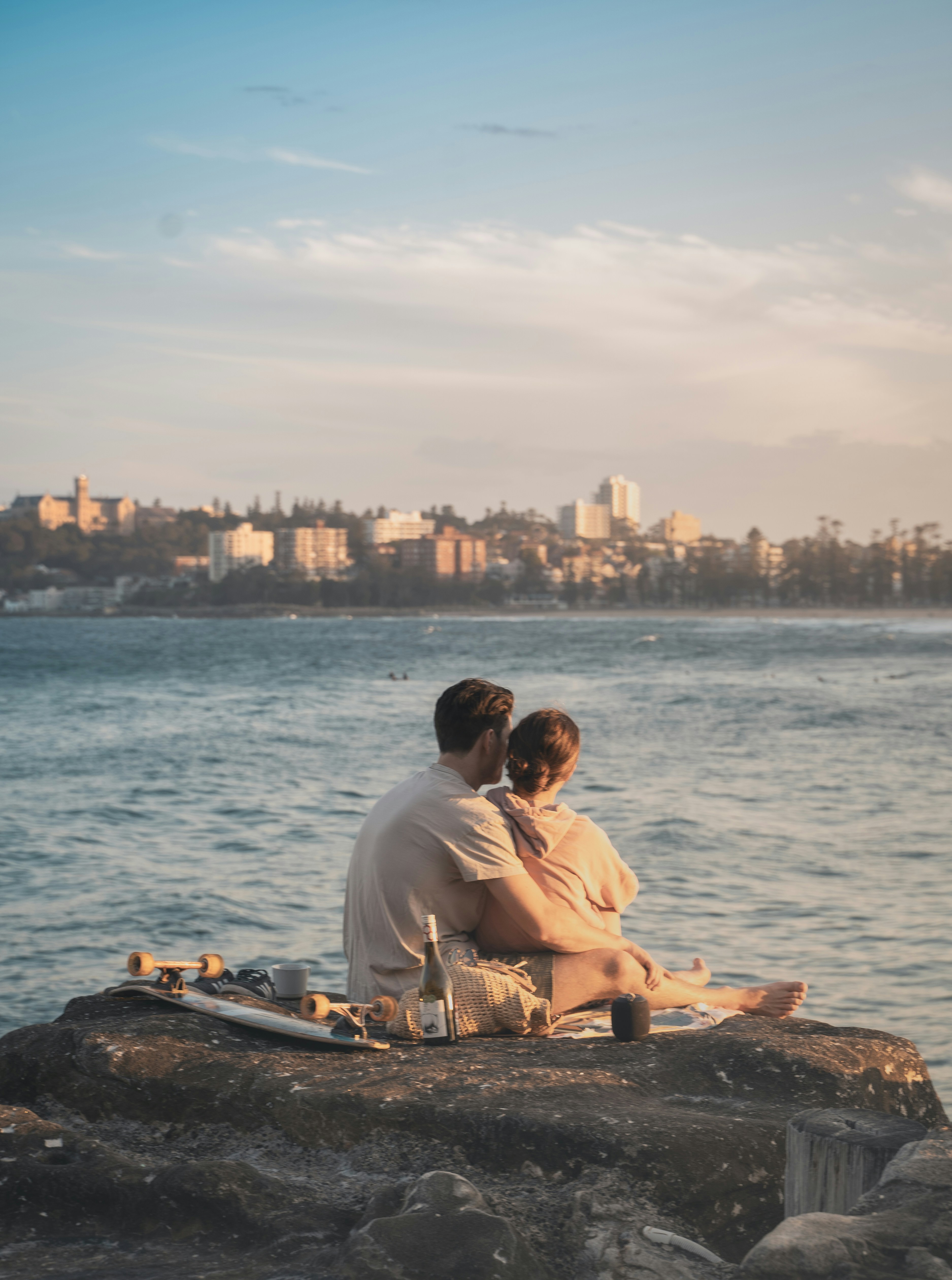 man-and-woman-sitting-on-rock-near-sea-during-daytime