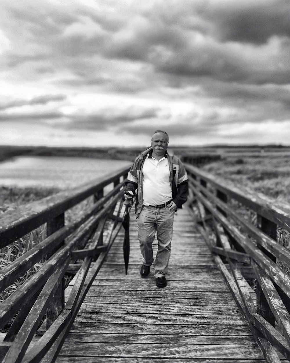 woman in black jacket and white pants walking on wooden bridge