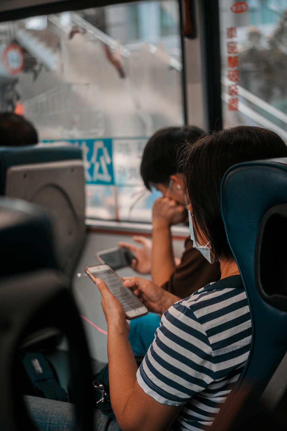 woman in white and black stripe shirt holding smartphone