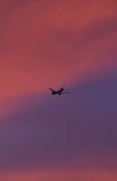 A colorful airplane flying over a vibrant sunset sky.