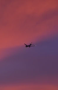 A colorful airplane flying over a vibrant sunset sky.