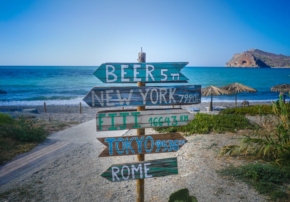 blue and white wooden beach signage on beach shore during daytime