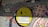 Graffiti art featuring a large yellow emoticon wearing a white face mask, painted on a gray wall. There are various colorful tags and writings in purple, red, and orange, including a large hash symbol and the word 'SATO' above the emoticon. Additionally, a speech bubble with text is located on the left side.