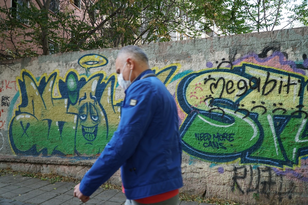 a man walking past a wall covered in graffiti