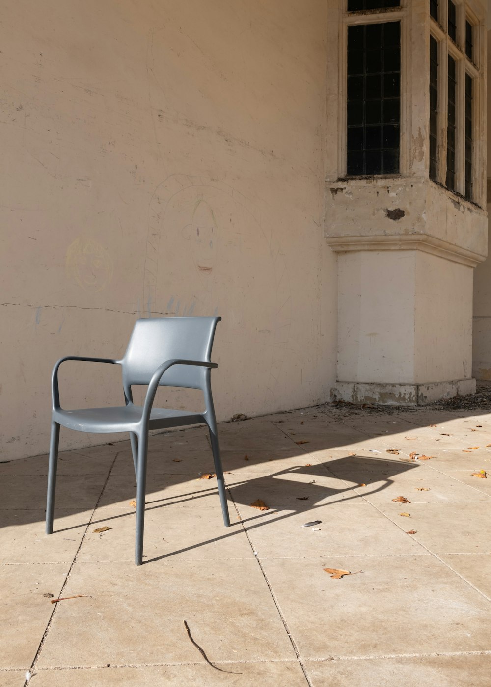 白いコンクリートの壁の横にある灰色のプラスチックの椅子
