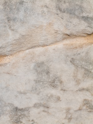 A textured surface with a mix of light and dark gray tones, featuring natural stone patterns and a subtle horizontal line running across.