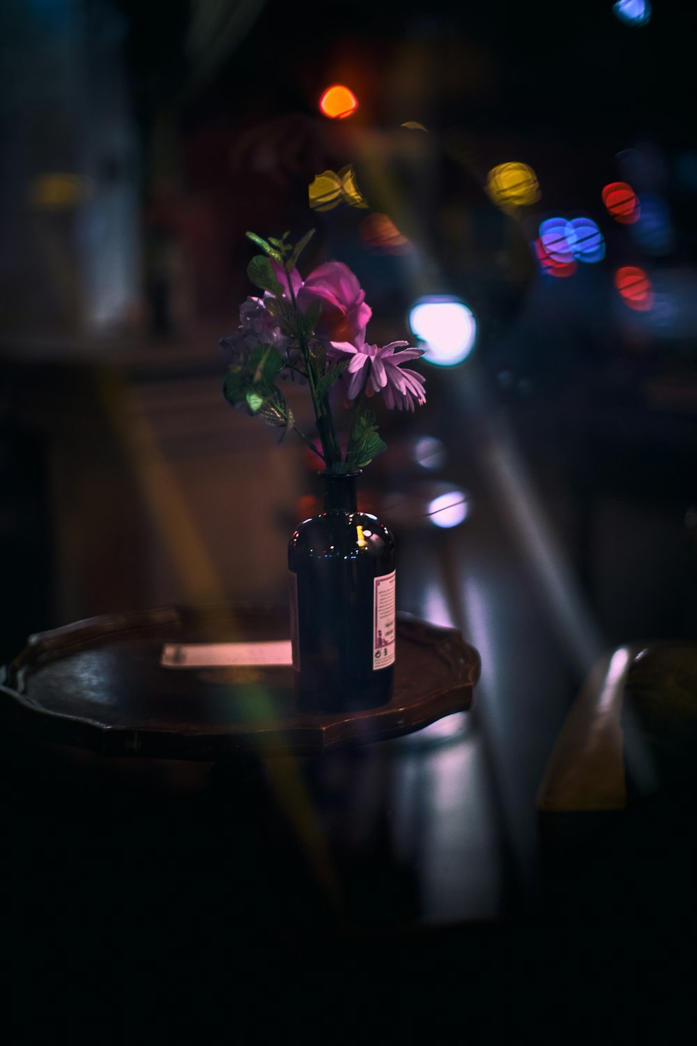 purple flowers in glass bottle on table